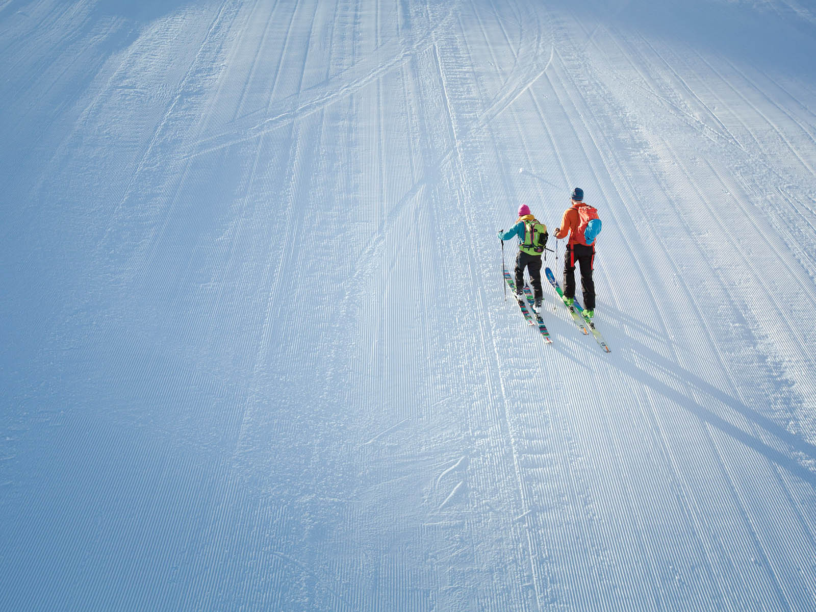 Two adults skiing uphill or skinning the mountain at Snow King Mountain in Jackson Hole, WY.