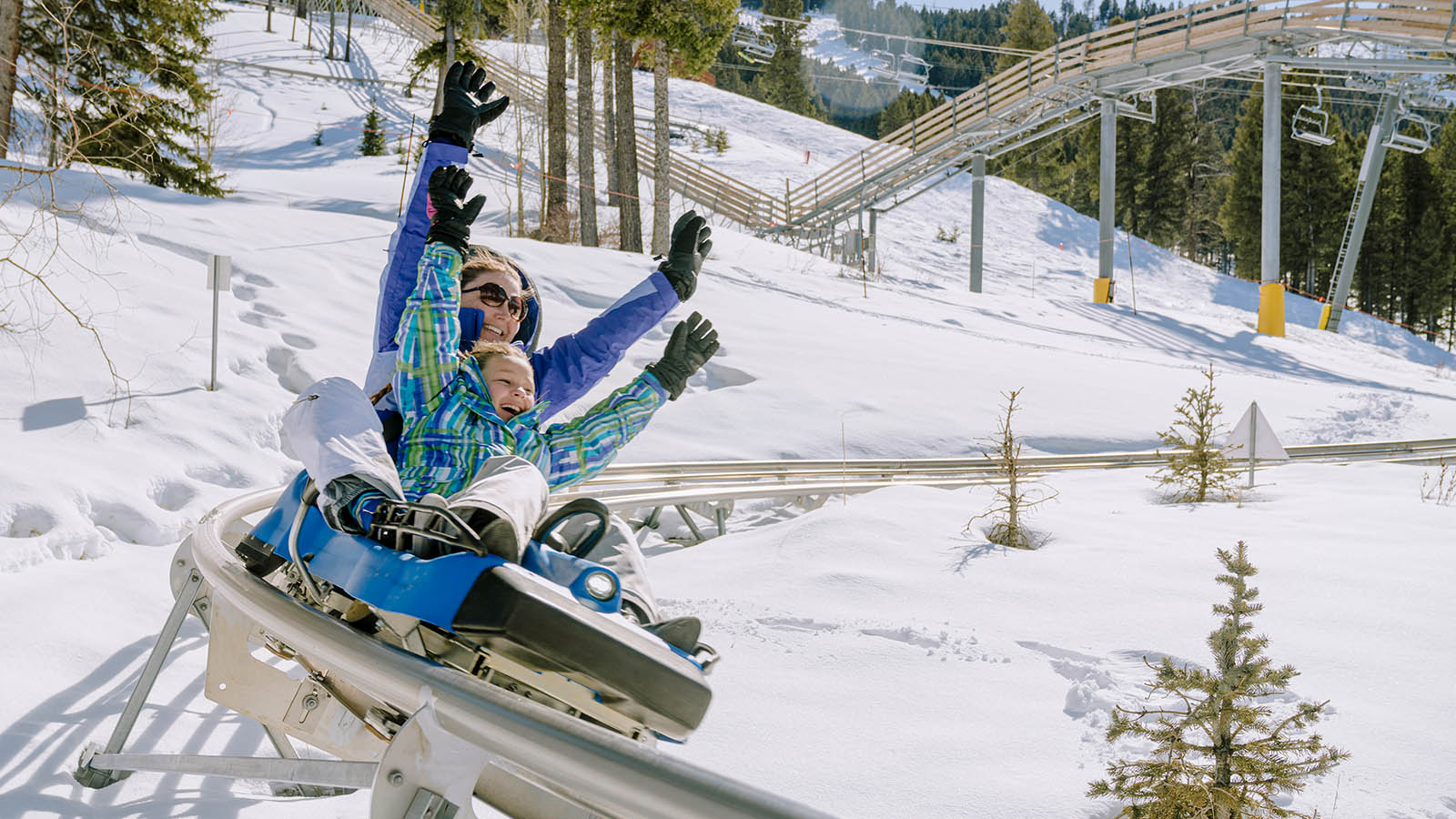 A mother and child ride down the Cowboy Coaser with their arms in the air at Snow King Mountain in Jackson Hole, WY.