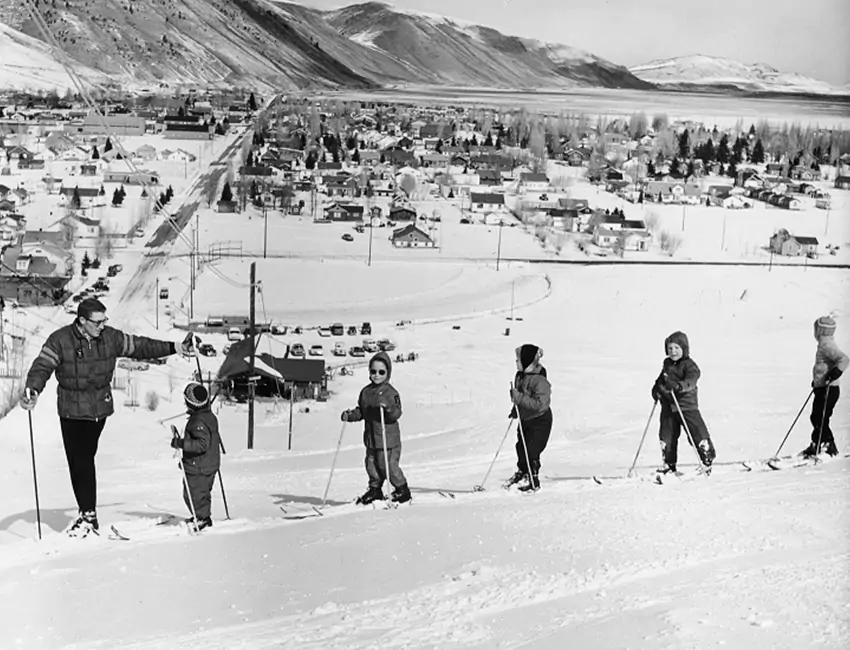 A ski instructor teaches children how to ski in a vintage black and white scene at Snow King Mountain in Jackson Hole, WY.