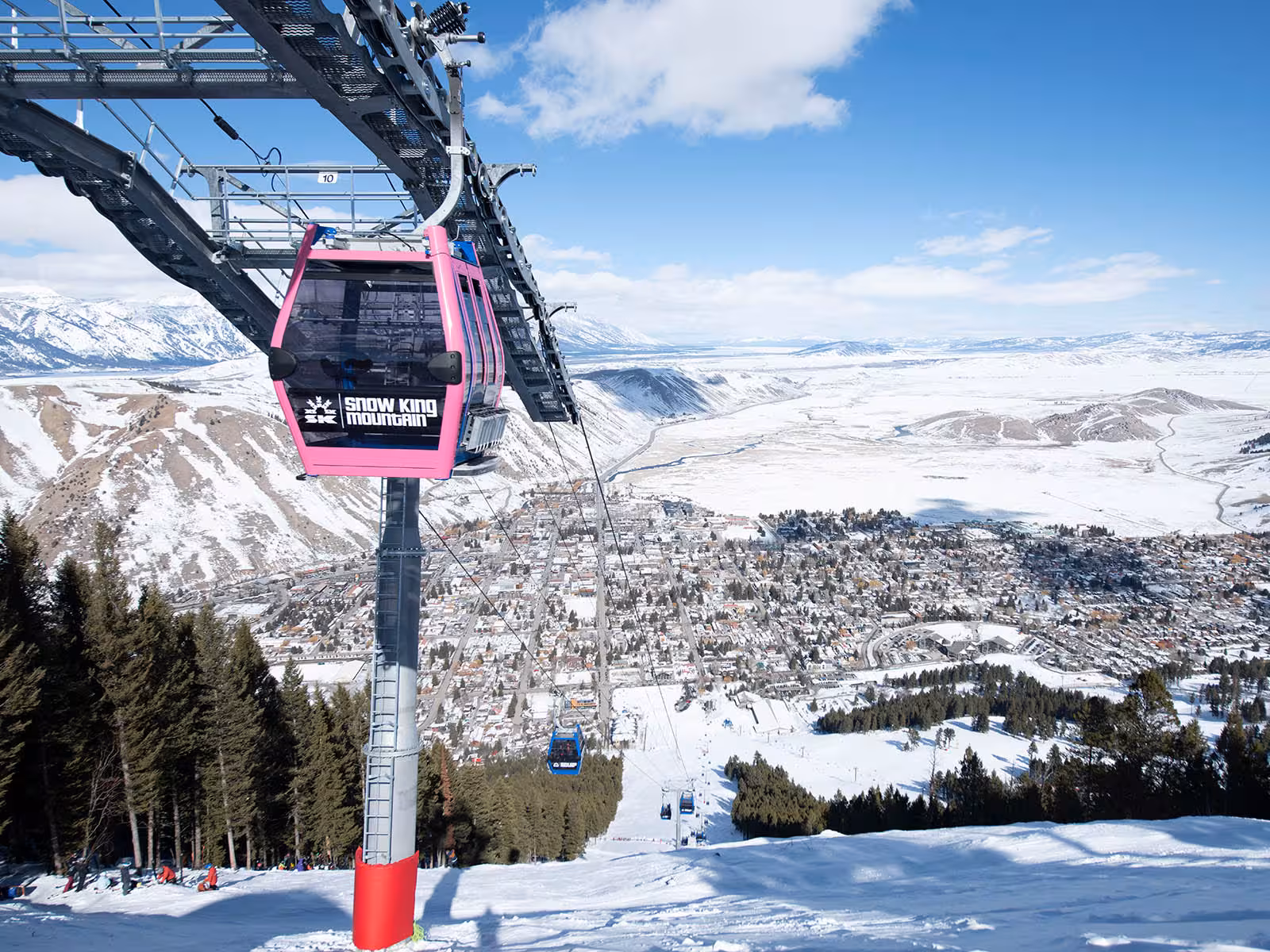 The Gondola at Snow King Mountain in Jackson Hole, WY goes down the side of the mountain with views of Jackson Hole covered in snow.